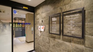 A hotel entrance with a glass door, a reception desk, and a wall-mounted phone. - SUPER HOTEL Kushiro Kurogane (Kushiro)