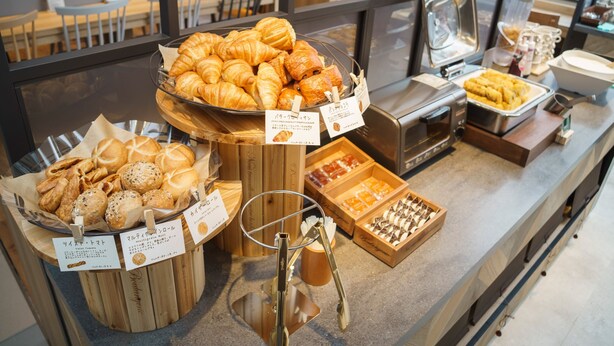A bakery display with various baked goods, including croissants and muffins, in a café setting. - SUPER HOTEL Kushiro Kurogane (Kushiro)