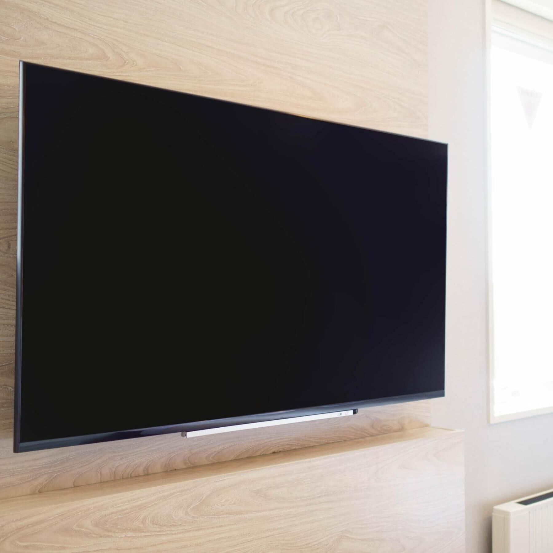 A flat-screen TV mounted on a wall with a wooden panel design.
