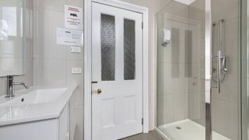 A bathroom with a white sink, a frosted glass door, and a glass-enclosed shower.