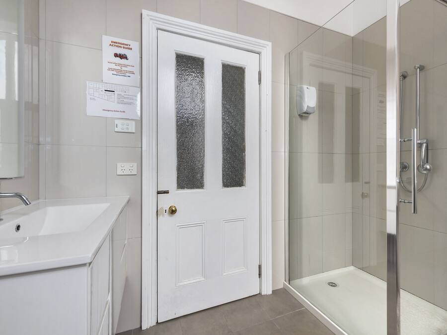 A bathroom with a white sink, a frosted glass door, and a glass-enclosed shower.