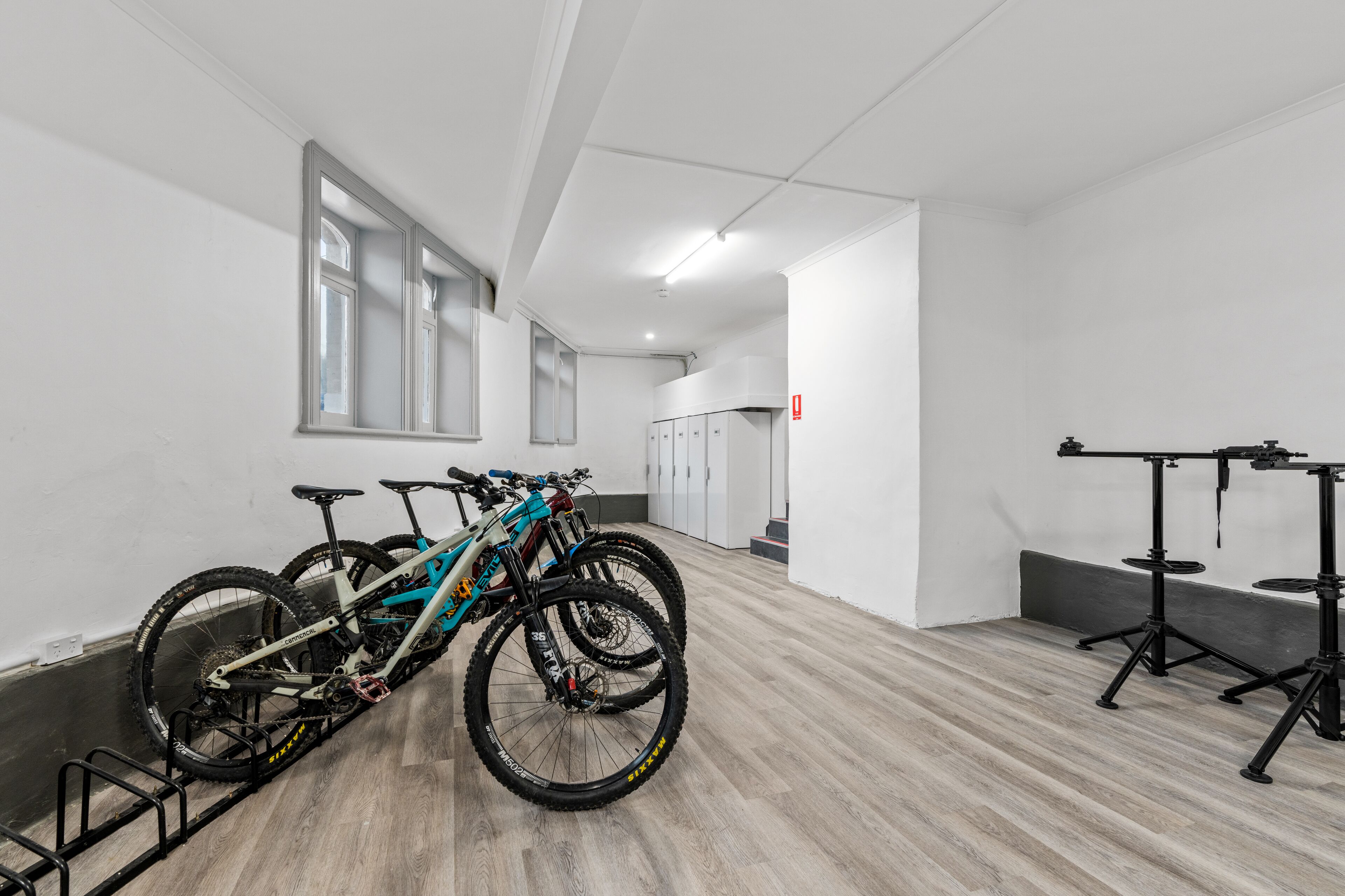 Una habitación amplia con suelo de madera, un soporte para bicicletas y una mesa con un trípode.