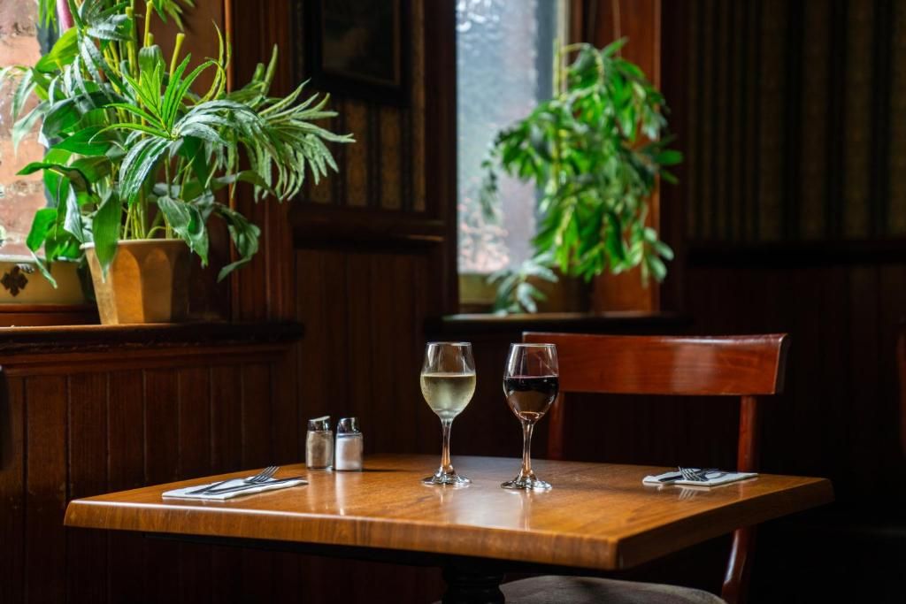 A wooden table with two glasses of white wine, salt and pepper shakers, and a menu.