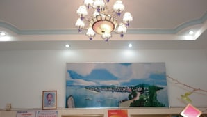 A hotel lobby with a large painting of a coastal scene, a chandelier, and various signs and decorations. - Hai Hien Guesthouse Phu Quoc (Phu Quoc)