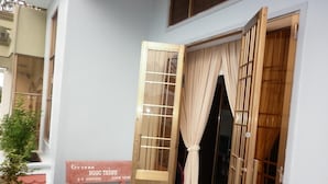 A wooden door with a curtain, a bench, and a sign with text. - Hai Hien Guesthouse Phu Quoc (Phu Quoc)
