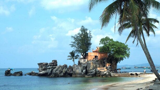 A coastal building with a rock base, surrounded by palm trees and boats in the water. - Hai Hien Guesthouse Phu Quoc (Phu Quoc)