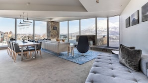 A modern living room with a large window, a dining area, and a sofa. - The Vale Niseko (Kutchan)