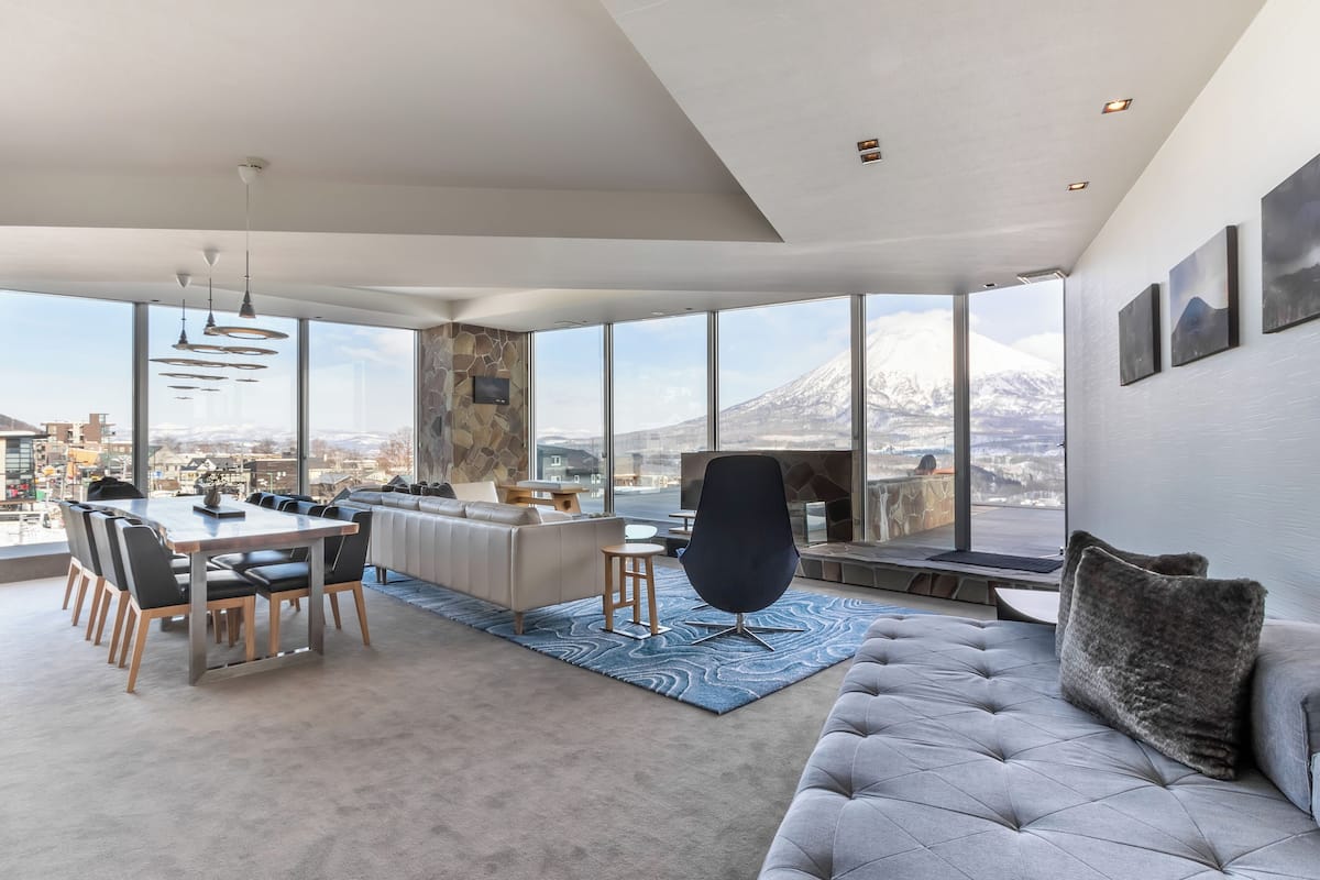 Una sala de estar moderna con un ventanal grande, una zona de comedor y un sofá.
