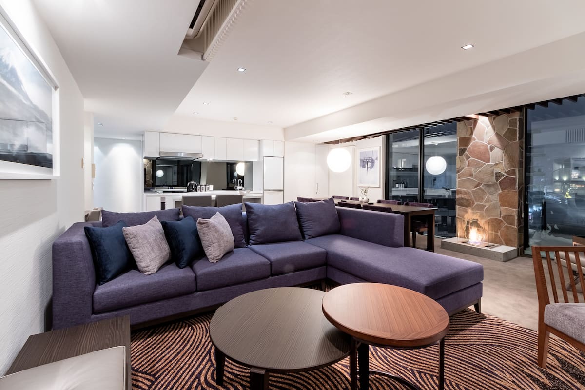 Una sala de estar moderna con un sofá modular, una mesa redonda de centro y una chimenea.