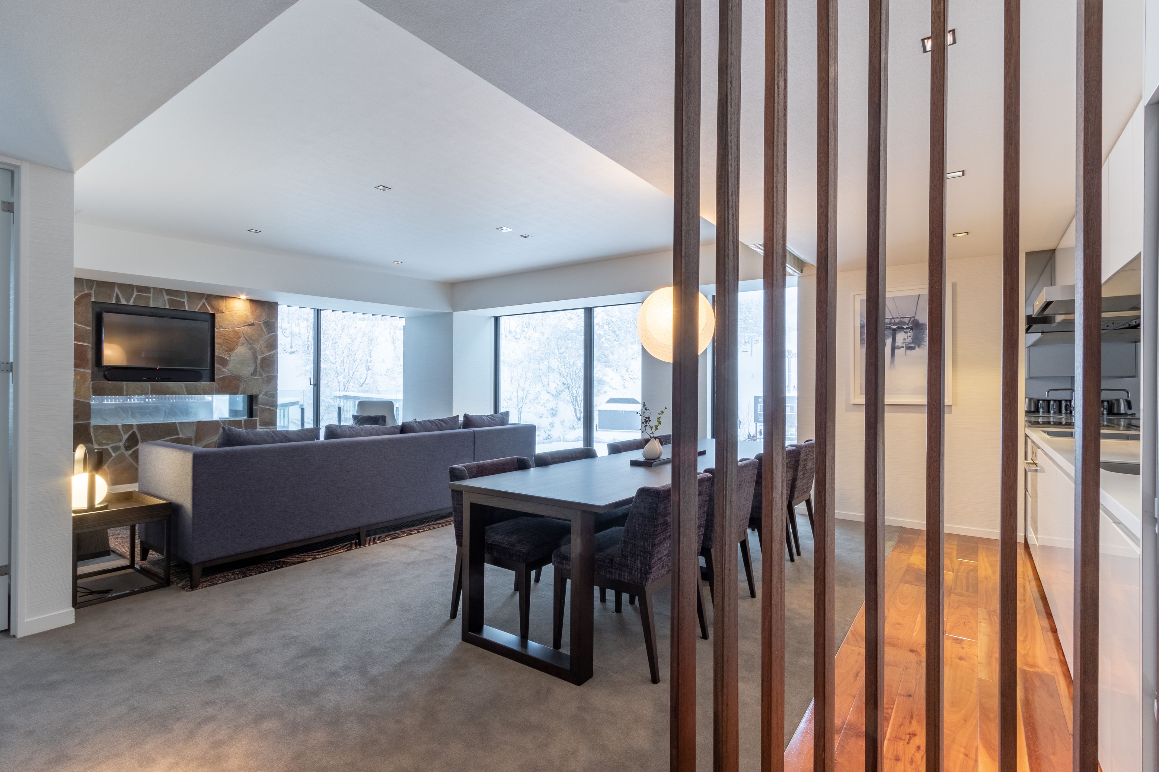 A modern living space with a dining area, a sofa, and a kitchen.