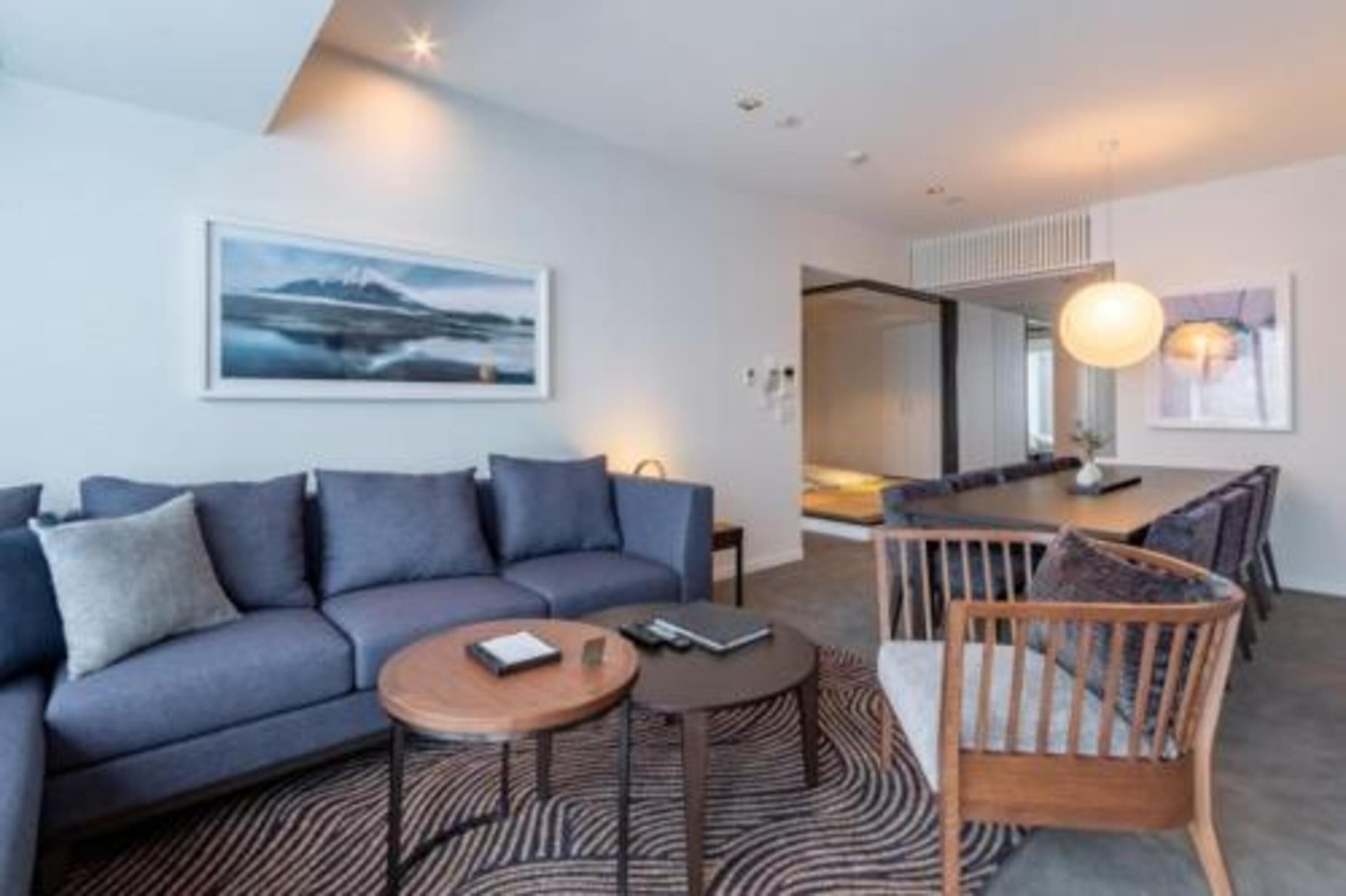 A modern living room with a sofa, coffee table, and a dining area with chairs and a table.