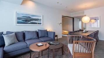 A modern living room with a sofa, coffee table, and a dining area with chairs and a table.