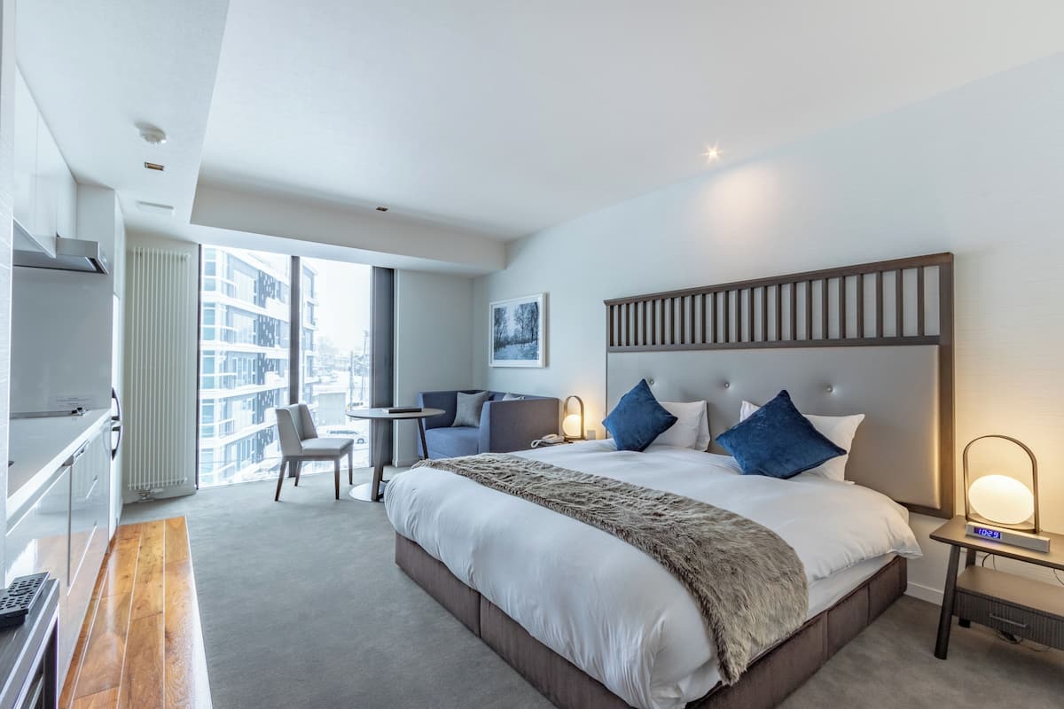Una habitación de hotel moderna con una cama grande, un escritorio, una silla y vistas a la ciudad.