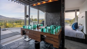A modern bathroom with a large window, a wooden vanity, and a stone backsplash. - The Vale Niseko (Kutchan)