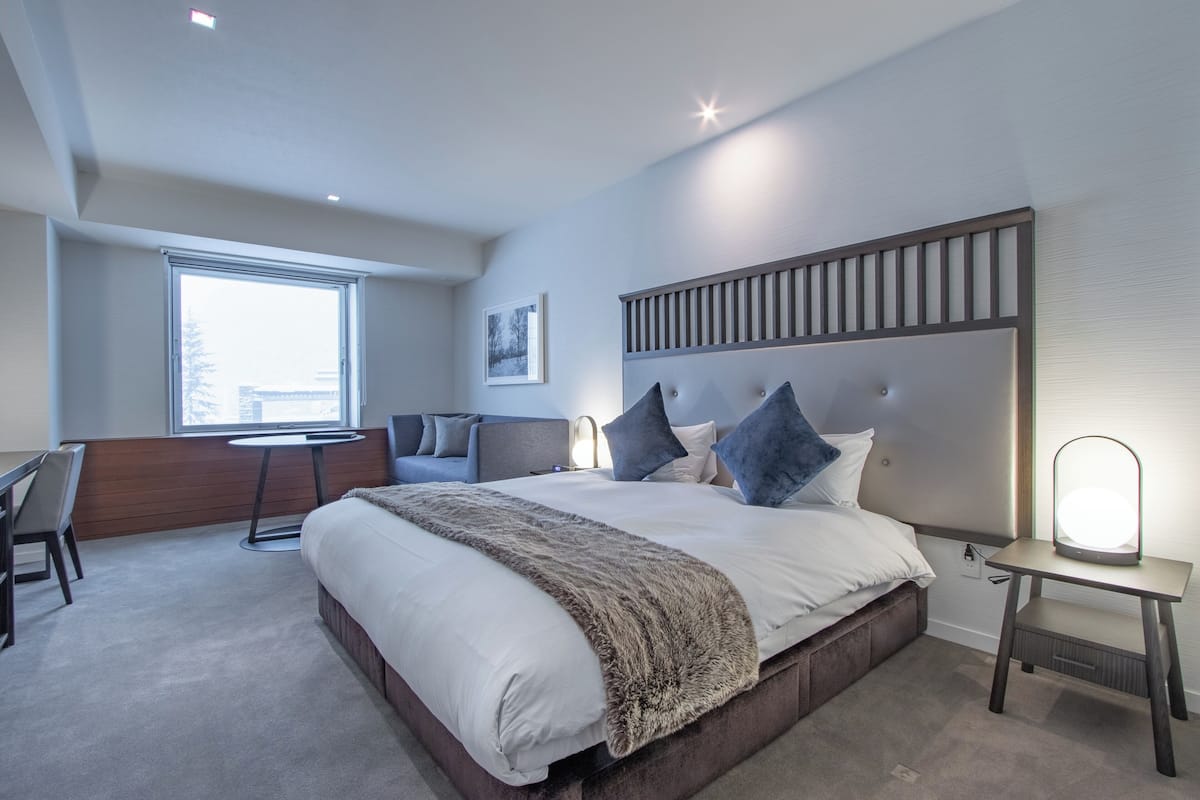 Una habitación de hotel moderna con una cama grande, un escritorio, una silla y una ventana.