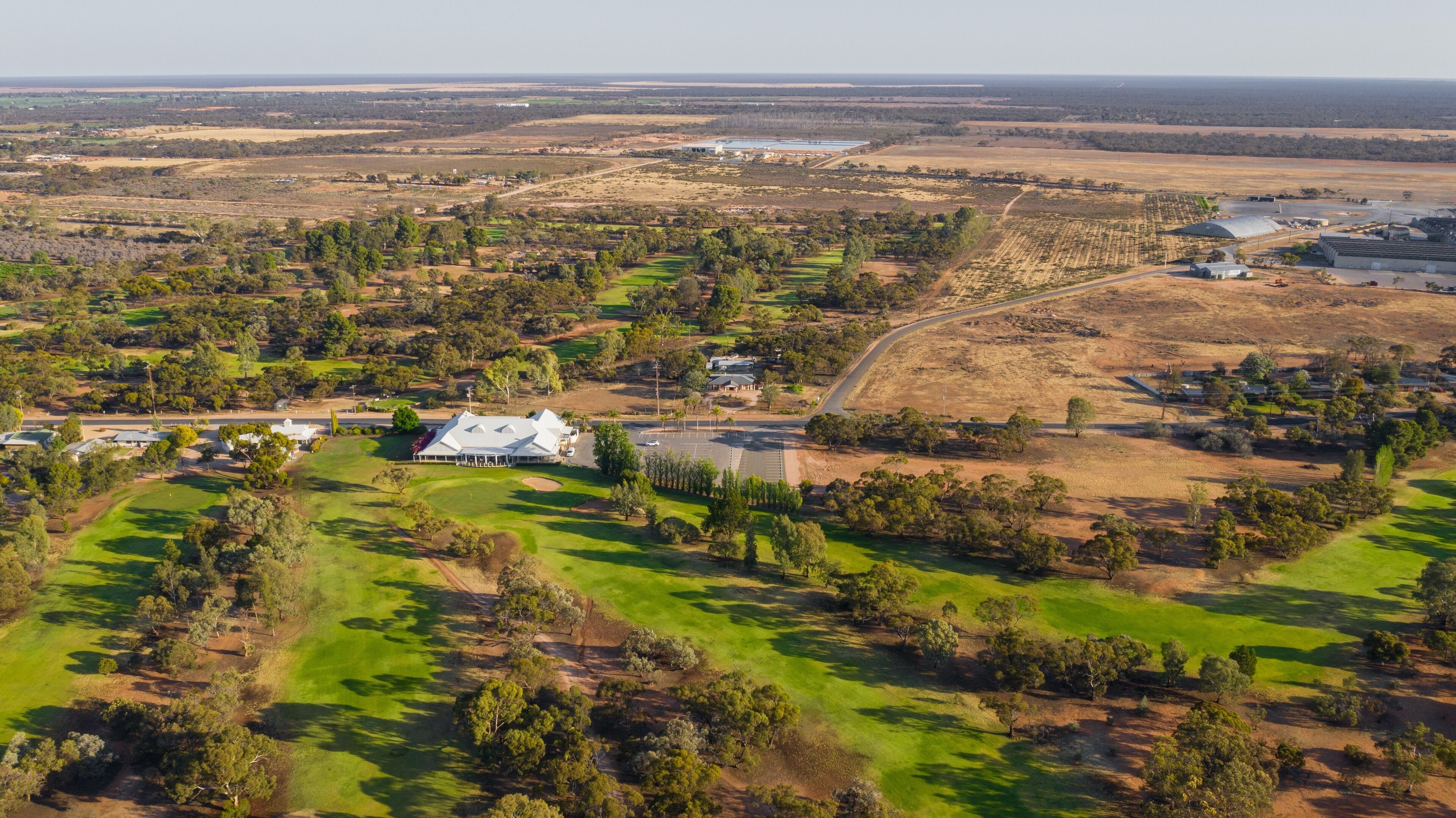 Vista aérea de uma propriedade rural com uma casa grande, campos verdes e árvores espalhadas.