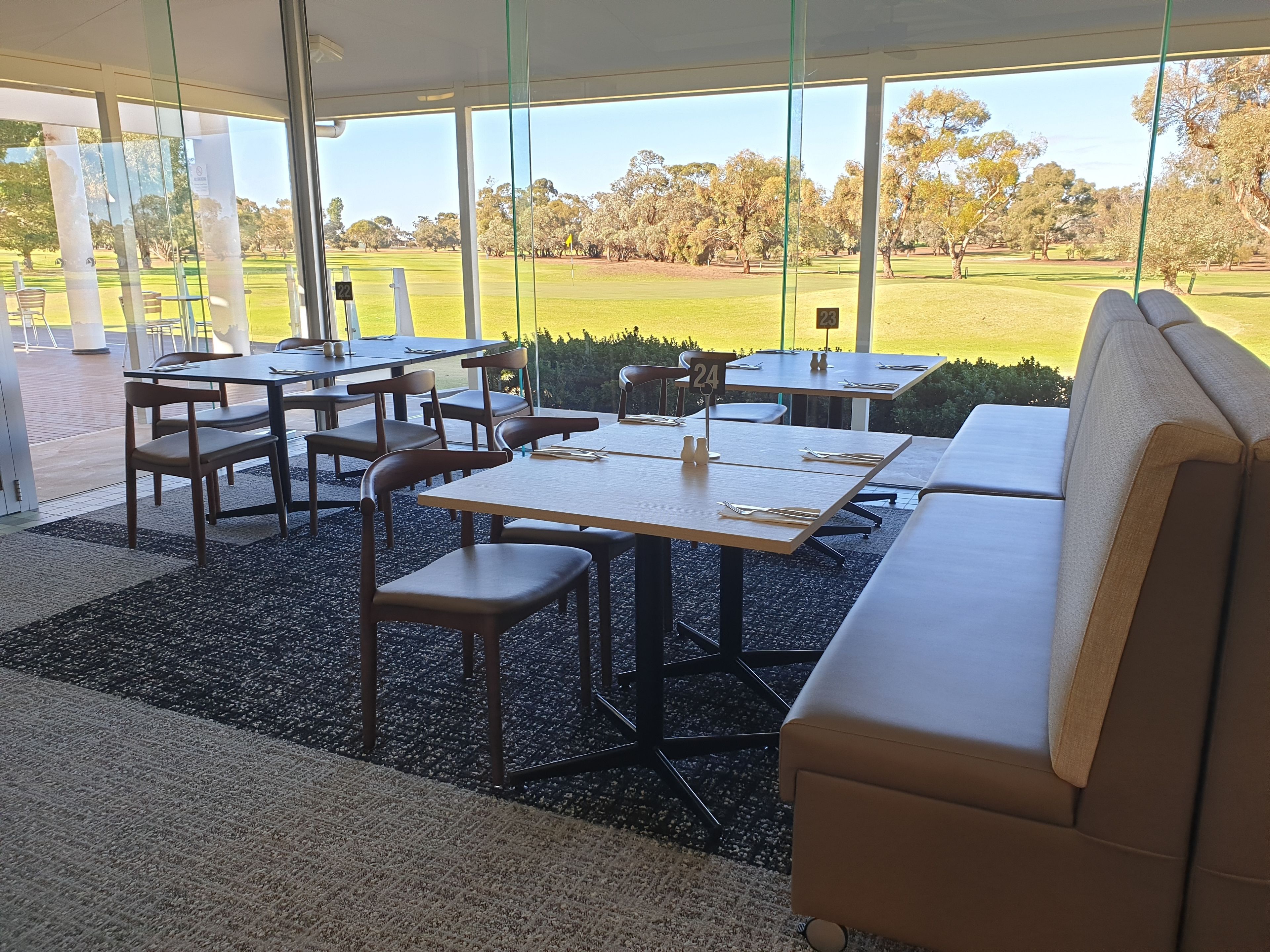 Un comedor moderno con mesas y sillas, y amplios ventanales que ofrecen vistas a un campo de golf.