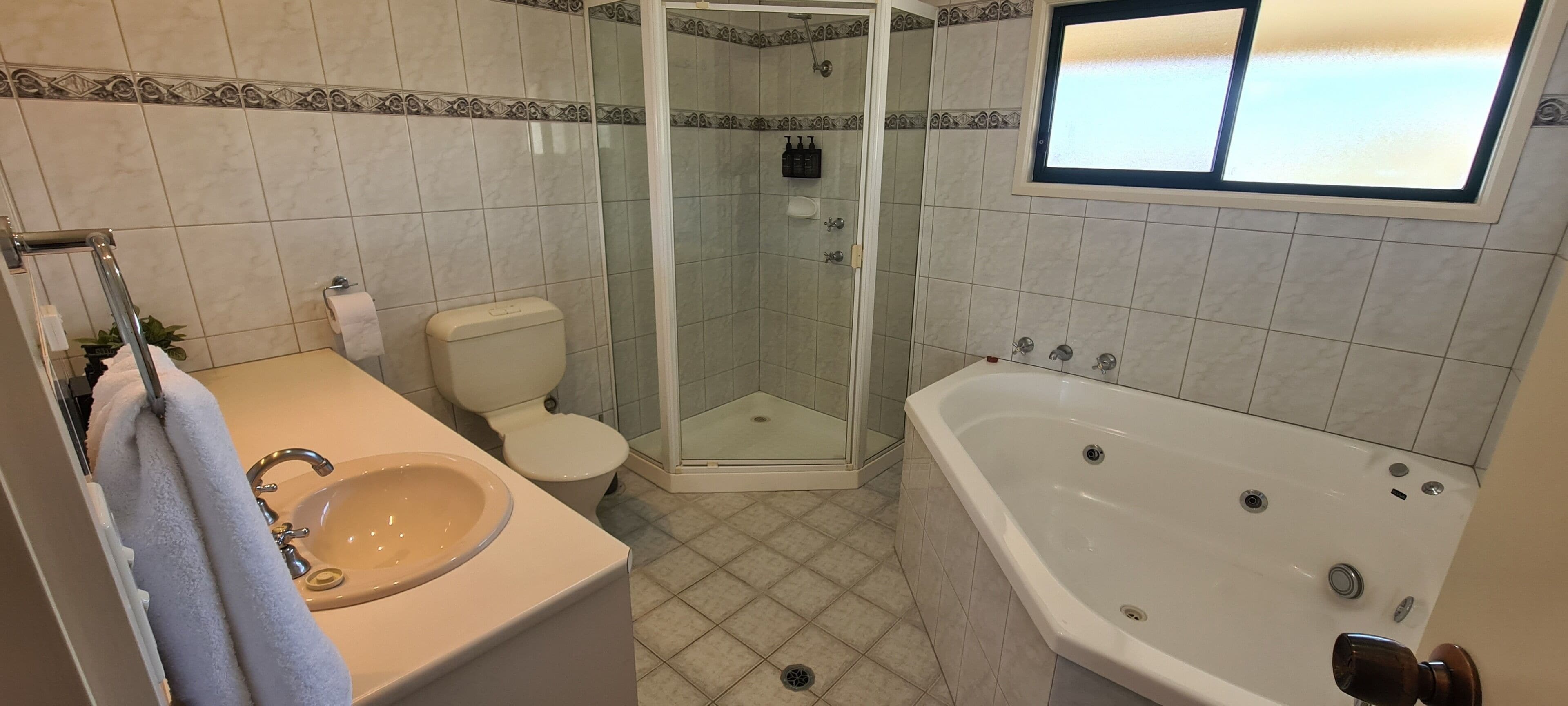 A bathroom with a glass-enclosed shower, a bathtub, a toilet, and a sink.