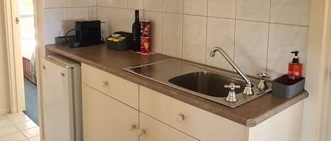 A kitchen with white cabinets, a stainless steel sink, and a refrigerator.
