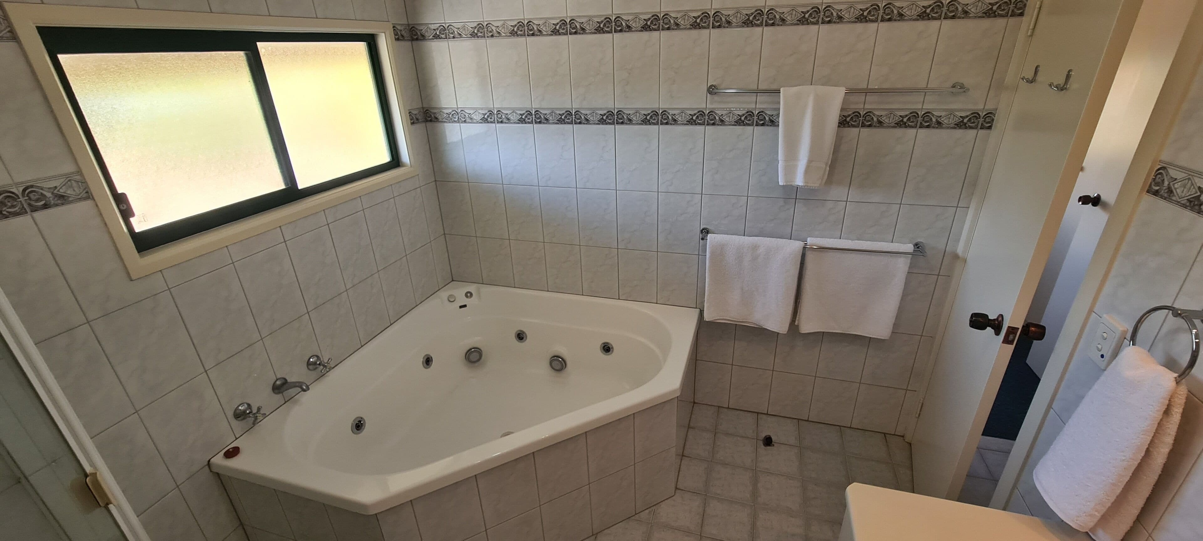 A bathroom with a bathtub, a window, and tiled walls.