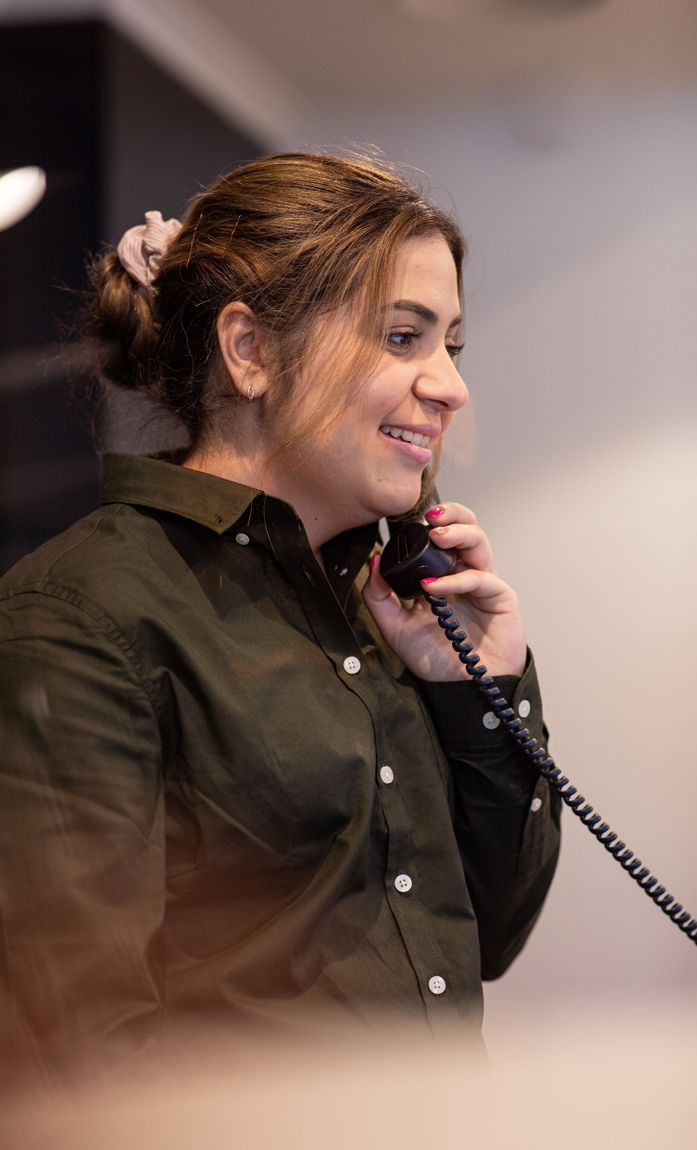 Une personne portant un t-shirt vert et tenant un téléphone.