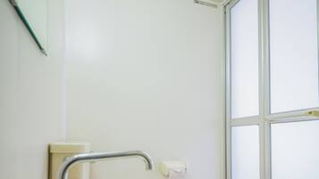 Un baño con lavamanos blanco, espejo y ventana.