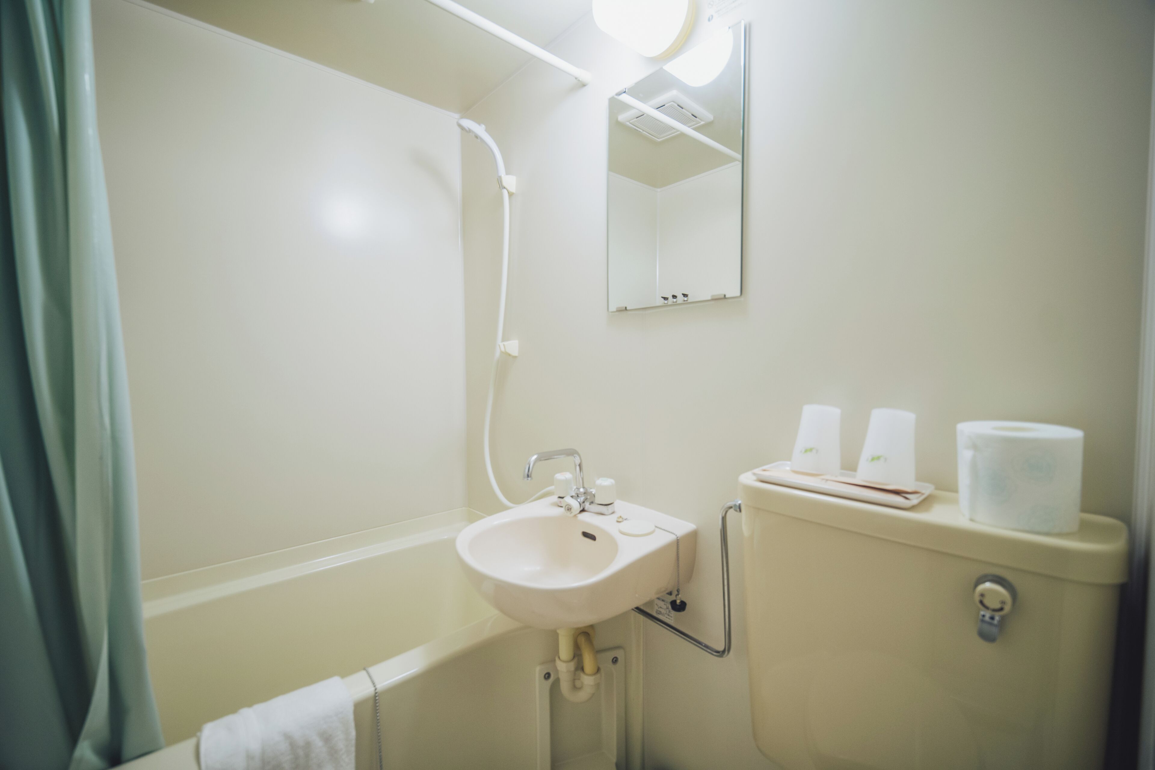 Un baño con lavamanos, espejo, inodoro y ducha.
