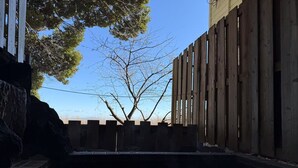 Una valla de madera con vista despejada a un árbol y una masa de agua tranquila al frente.