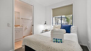 Une chambre à coucher avec un lit, une fenêtre donnant sur un beau paysage, une table de chevet et une commode.