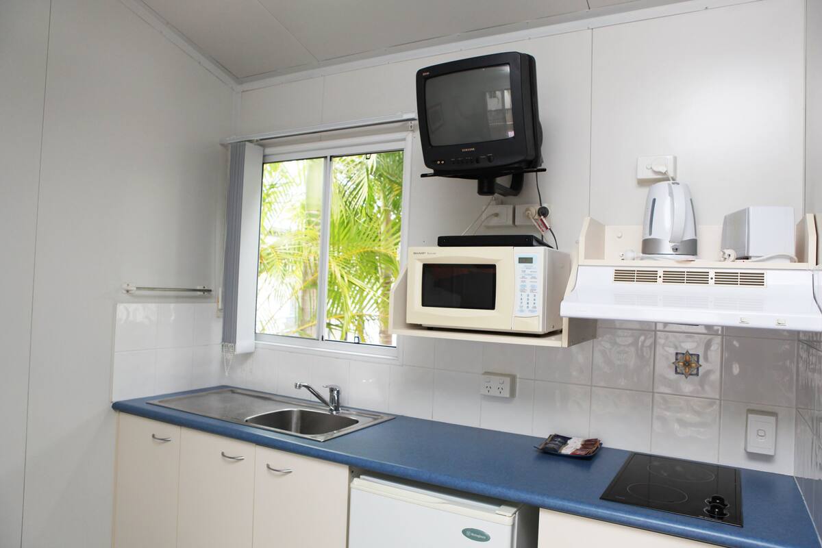 Una cocina equipada con microondas, cafetera y lavabo.