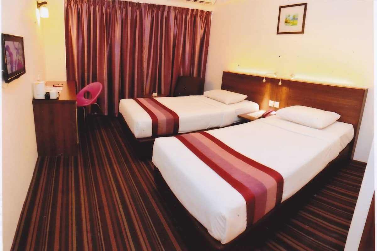 A hotel room with two beds, a wooden headboard, a striped carpet, a pink chair, and a framed picture on the wall.