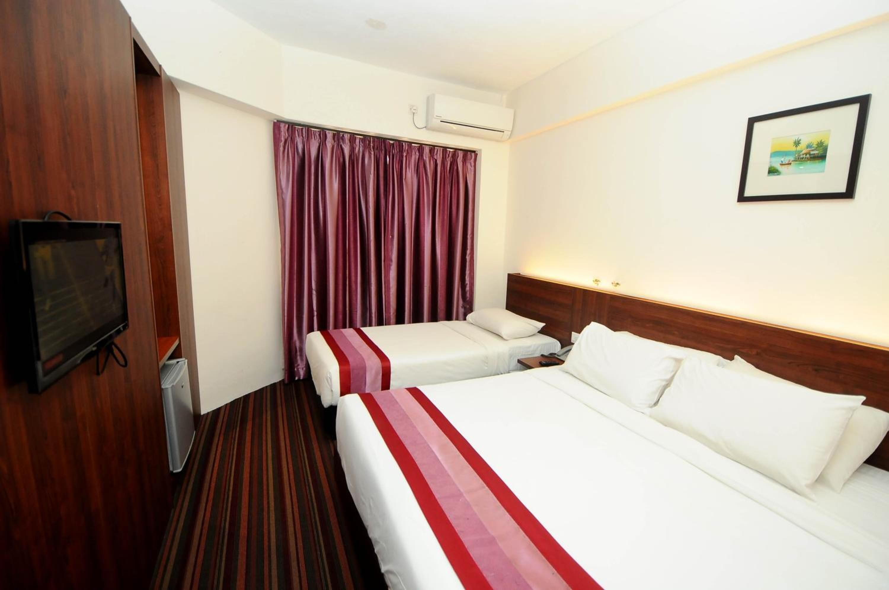 A hotel room with two beds, a television, an air conditioning unit, and a framed picture on the wall.