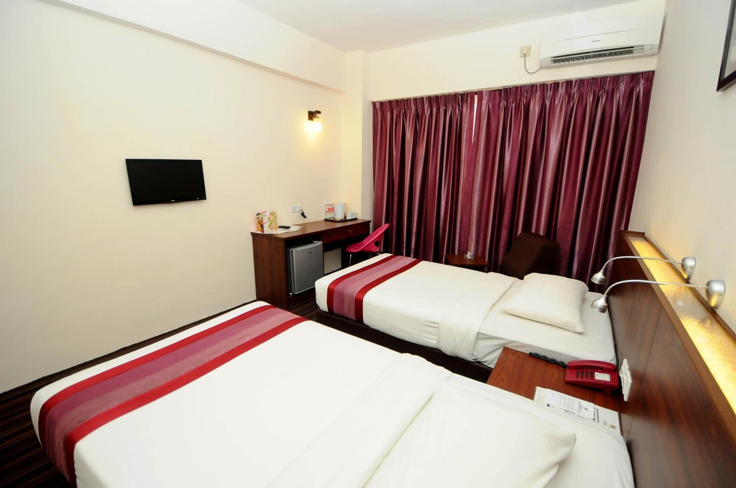 A hotel room with two beds, a desk with a computer, a TV, and a telephone.