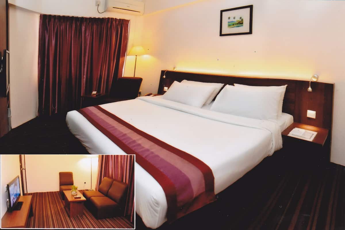 A hotel room with a large bed, a nightstand, a desk with a chair, a lamp, and a picture on the wall.