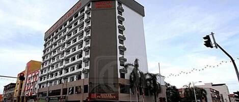 A multi-story hotel with a prominent red and white sign, multiple balconies, and a ground-level restaurant.
