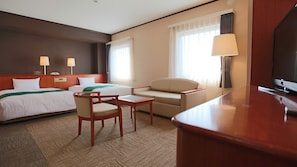 A hotel room with two beds, a sofa, a chair, a small table, a TV, and two lamps. - Kura Hotel Ichinoseki (Ichinoseki)