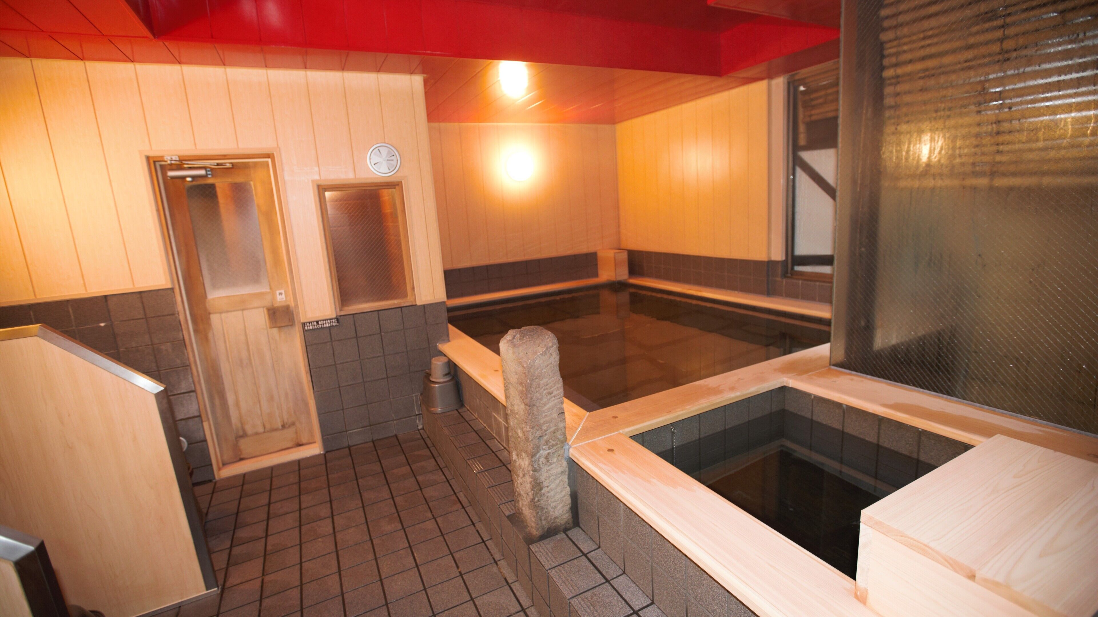 Una sala de sauna con banco de piedra, suelo de baldosas y paredes de madera.