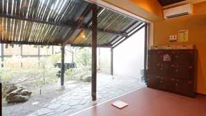 Un espacio al aire libre cubierto con suelo de piedra, un banco de madera y una fila de taquillas numeradas.