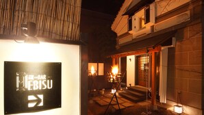 Un edificio japonés tradicional con un cartel, estructura de madera y entrada iluminada.