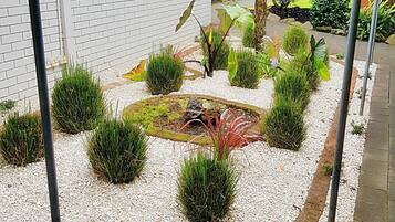Ein Garten mit Backsteinmauer, unterschiedlichen Pflanzen und einem kleinen Teich.