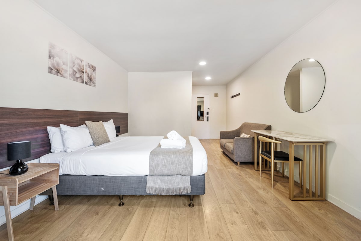 Una habitación de hotel moderna con una cama grande, un escritorio y una silla.