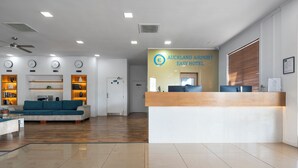 A modern hotel lobby with a reception desk, seating area, and clocks on the wall. - Auckland Airport Easy Hotel (Auckland)