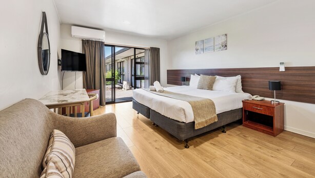 A modern hotel room with a large bed, a desk, a chair, and a nightstand. - Auckland Airport Easy Hotel (Auckland)