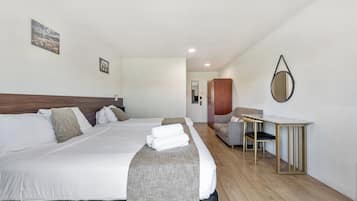 Une chambre d’hôtel avec deux lits, un bureau et une chaise.
