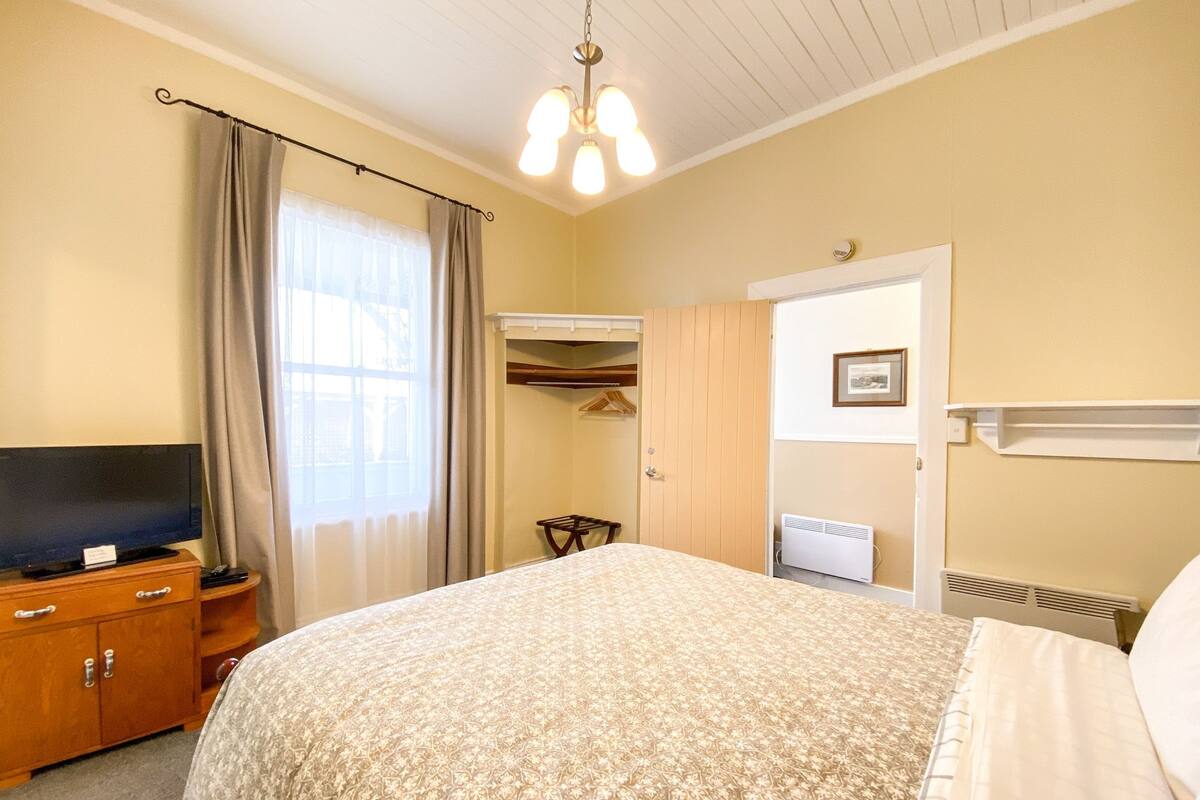 Een hotelkamer met een groot bed, een televisie op een houten kast, een kledingkast en een radiator.