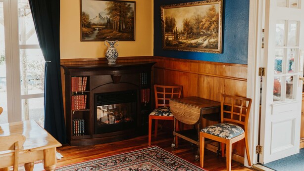 Une pièce chaleureuse avec une cheminée, des étagères à livres, une table à manger et un tapis à motifs.
