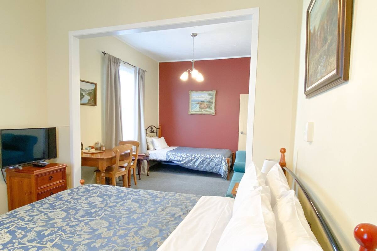 Een hotelkamer met een bed, een bureau met stoel, een televisie en een schilderij aan de muur.