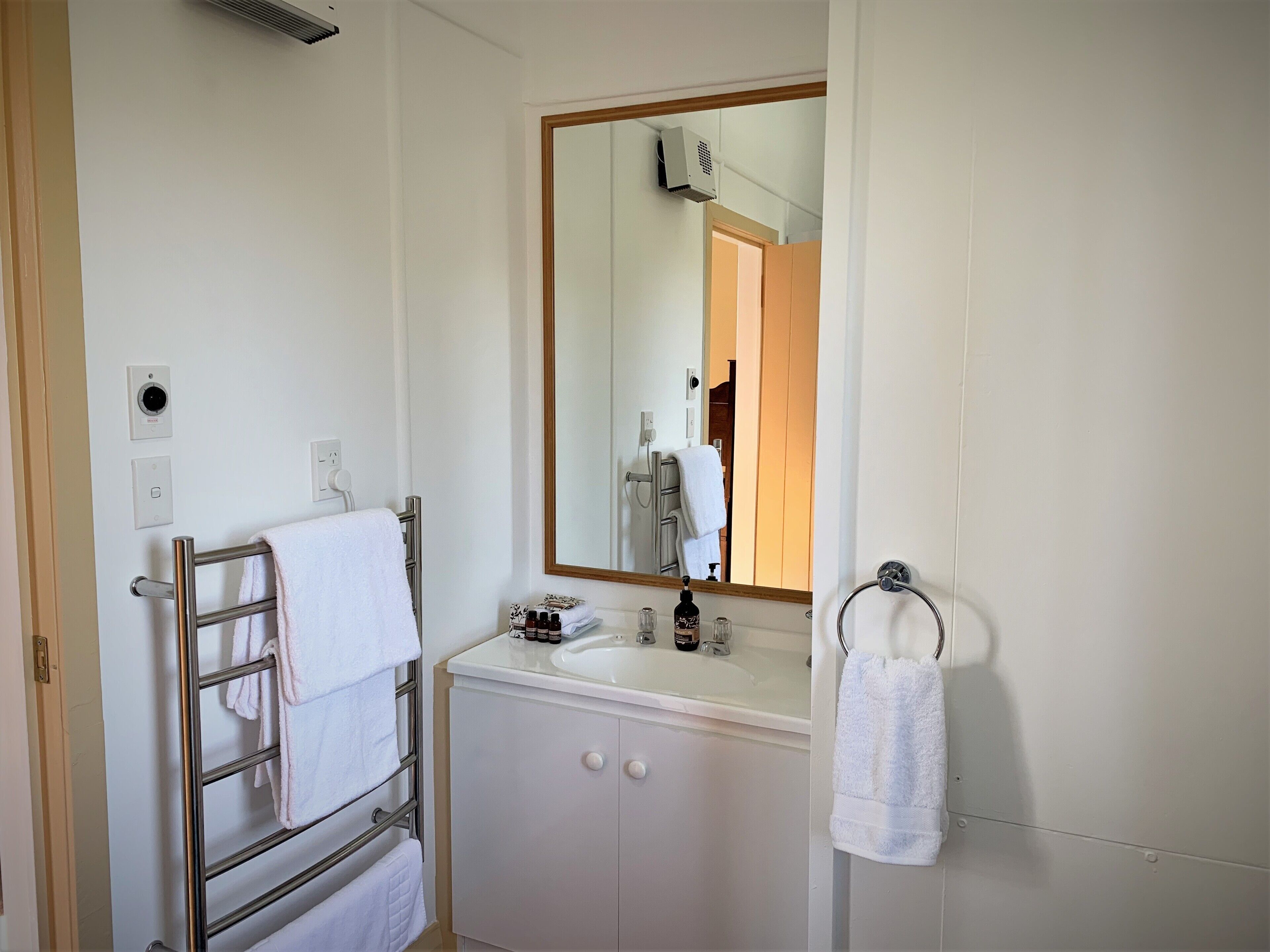 A bathroom with a white sink, a mirror, and a towel rack.