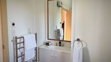 A bathroom with a white sink, a mirror, and a towel rack.