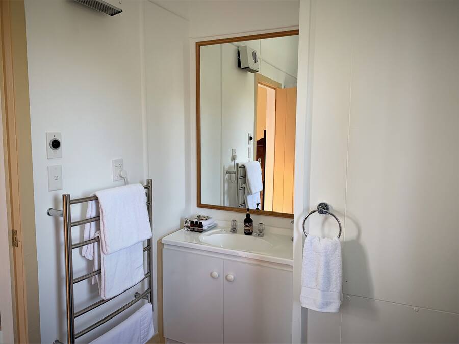 A bathroom with a white sink, a mirror, and a towel rack.